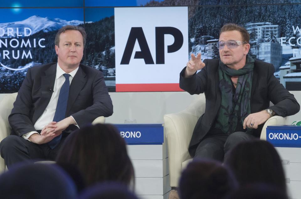 British Prime Minister David Cameron, left, listens to rock star Bono during the panel discussion "The Post-2015 Goals: Inspiring a New Generation to Act", the fifth annual Associated Press debate, at the World Economic Forum in Davos, Switzerland, Friday, Jan. 24, 2014. (AP Photo/Michel Euler)