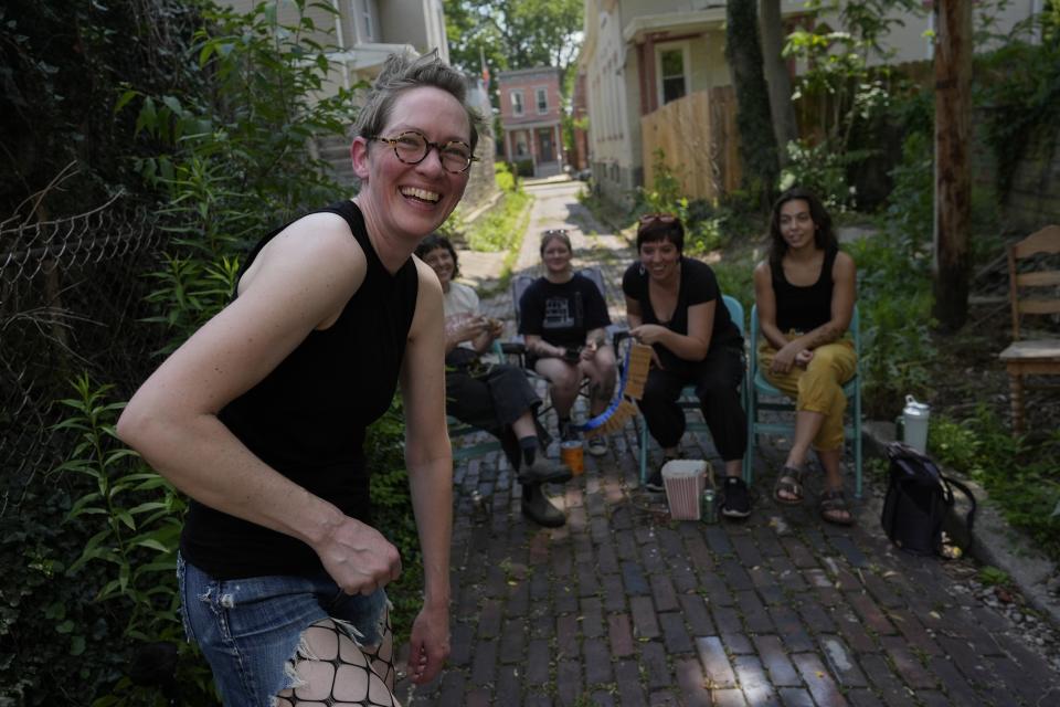 Renee Martin, left, laughs after performing her cicada striptease in fishnet stockings and a cicada nymph puppet costume in a Cincinnati ally on Tuesday, June 4, 2024. Audience members seated from left are, Lizzy DuQuette, Kalie Krause, Courtney Combs-Mock and Rae Fisher. The periodical cicadas that have blanketed parts of the American Midwest this spring are strange creatures, but they have nothing on some of their superfans. (AP Photo/Carolyn Kaster)