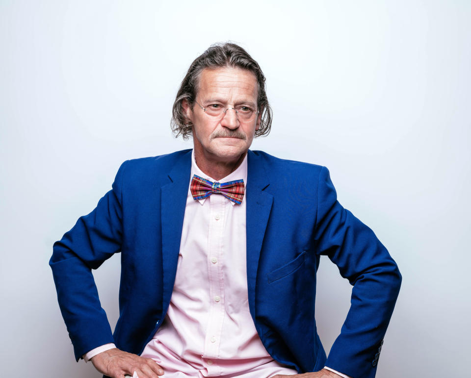 Man in business attire with bow tie, seated, looking at camera