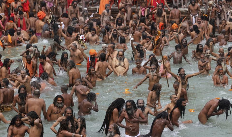 Crowds of people stand waist-deep in the Ganges River