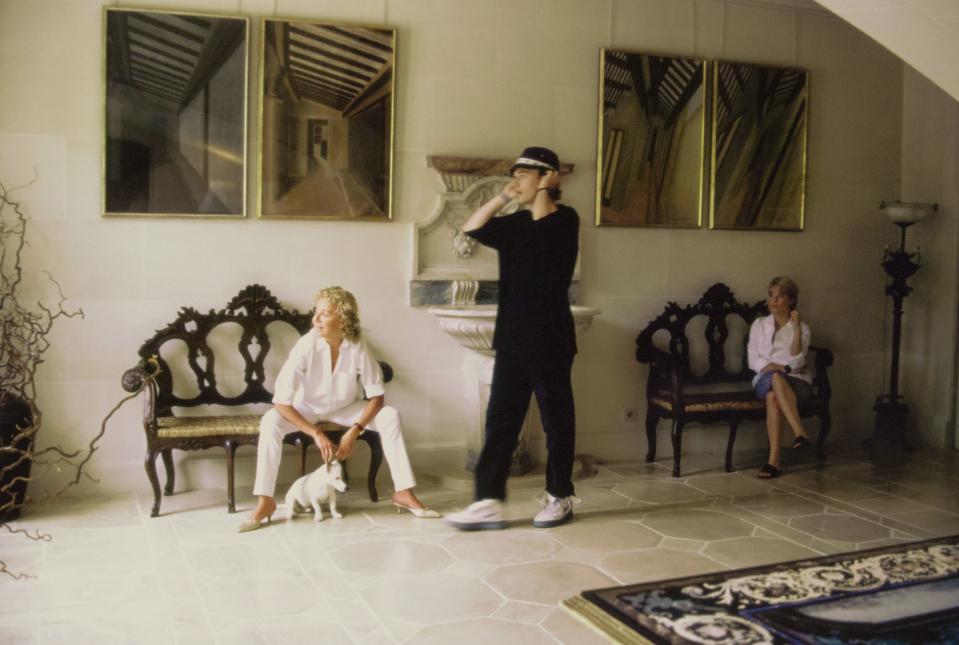 Lorenzo Fanfani, student, and Veronica Fanfani, fashion editor, the children of Laura Ungaro from her first marriage, stand with her in the entrance hall of the Paris, France, home she shares with her second husband, fashion designer Emanuel Ungaro, and their daughter Cosima. Two ornately carved wooden benches flank a marble fountain. On the wall hang four paintings of architectural spaces by Eugenio Ungaro, Emanuel's brother. Hair by Kerry Warn at John Frieda using John Frieda products. Makeup by Alan Milroy for Faces.