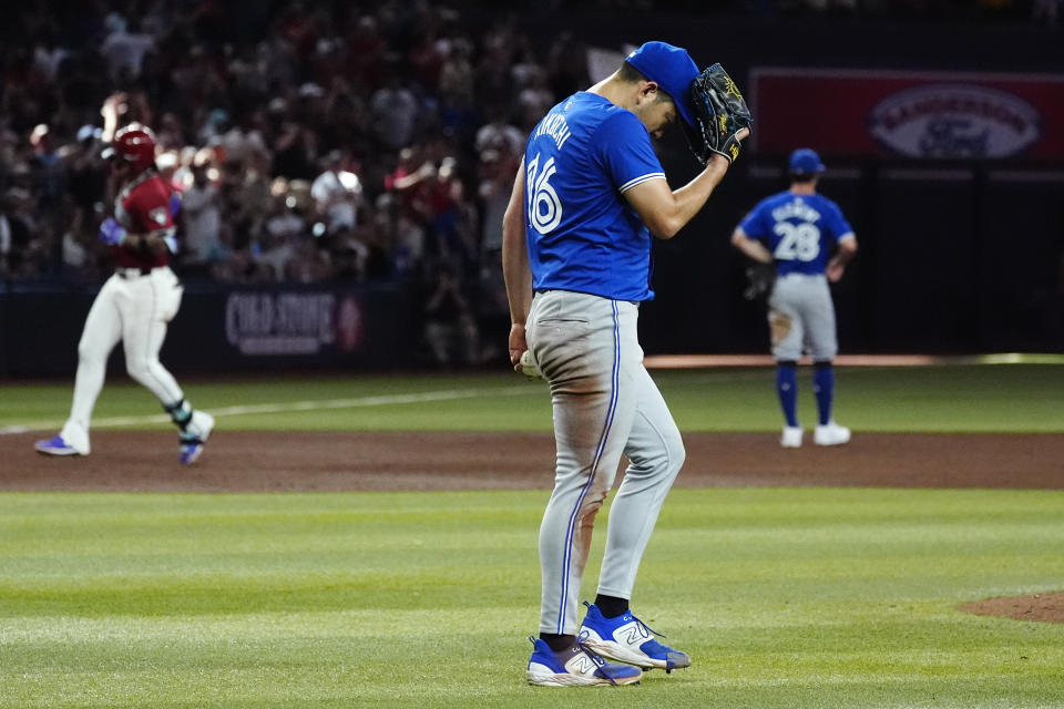 Toronto Blue Jays starting pitcher Yusei Kikuchi, center, reacts after giving up a grand slam against Arizona Diamondbacks' Ketel Marte, left, as Blue Jays third baseman Ernie Clement (28) watches the home run during the fifth inning of a baseball game, Sunday, July 14, 2024, in Phoenix. (AP Photo/Ross D. Franklin)