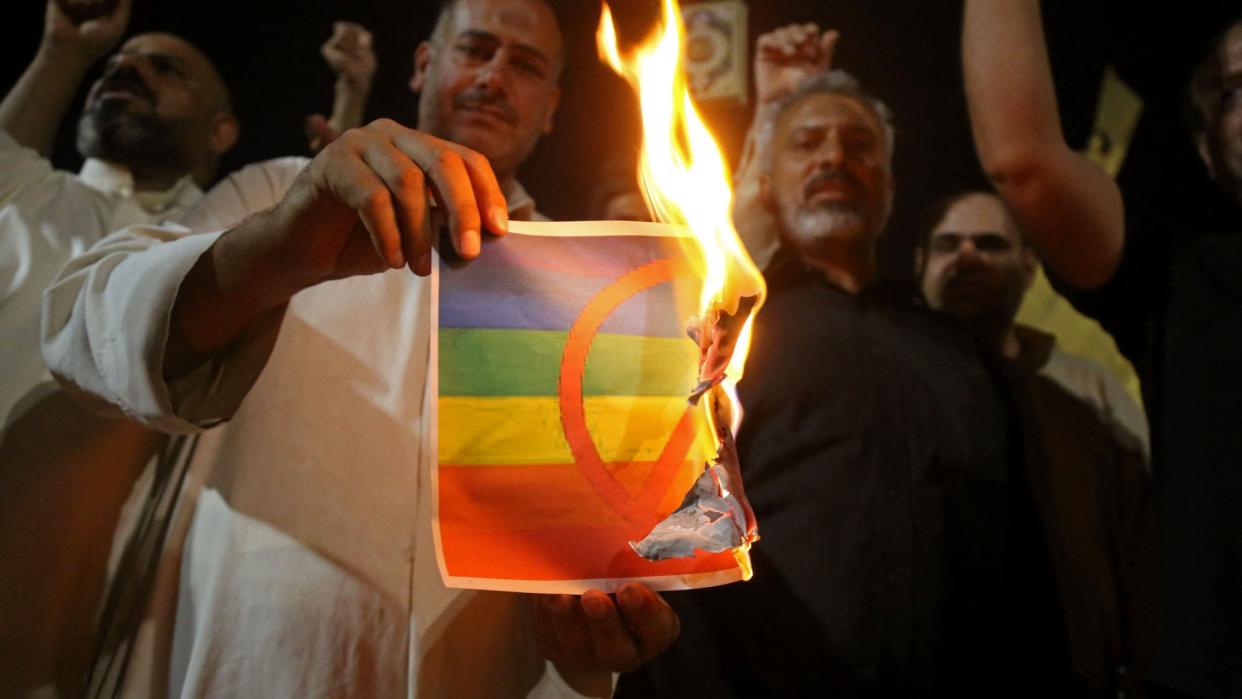  Supporters of Iraqi Shia cleric Moqtada Sadr burn a poster depicting an LGBTQ+ flag during a protest in Karbala on 29 June 2023. 