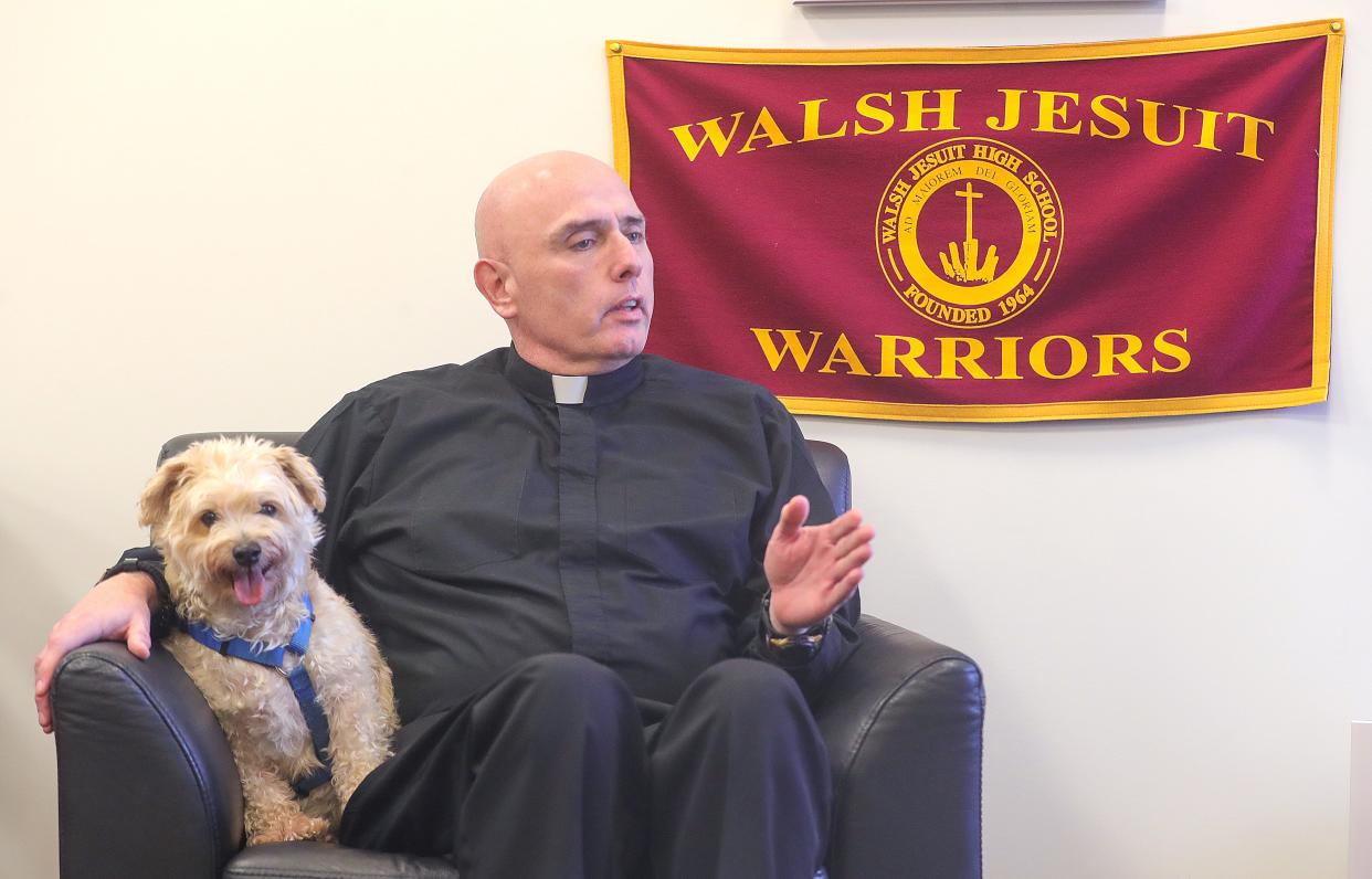 The Rev. Christopher Fronk sits with his dog Shipmate as he talks about becoming president of Walsh Jesuit High School this year on Thursday in Cuyahoga Falls.