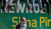 A masked man stands in front of a banner during a gathering celebrating Newroz, which marks the arrival of spring and the new year, in Diyarbakir, Turkey March 21, 2018. REUTERS/Umit Bektas