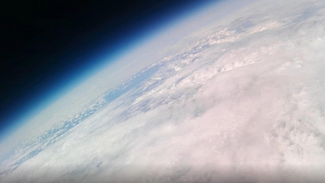  View of a cloudy sliver of Earth against the blackness of space. 