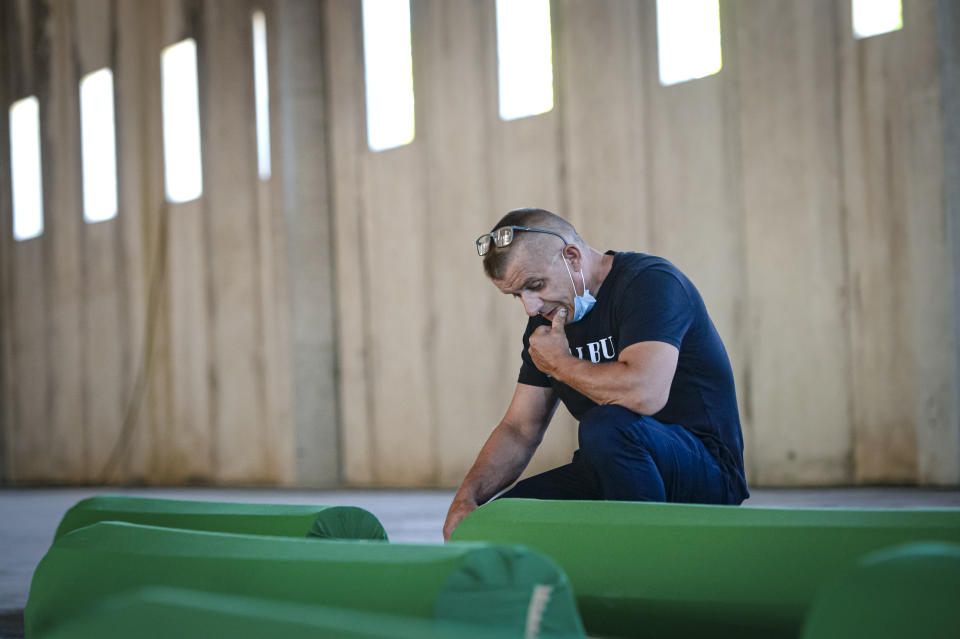 Survivor Bahrudin Salihovic sits by the coffin of his father, inside the former UN base in Potocari, near Srebrenica, Bosnia, Friday, July 10, 2020. Nine newly found and identified men and boys will be laid to rest when Bosnians commemorate on Saturday 25 years since more than 8,000 Bosnian Muslims perished in 10 days of slaughter, after Srebrenica was overrun by Bosnian Serb forces during the closing months of the country's 1992-95 fratricidal war, in Europe's worst post-WWII massacre. (AP Photo/Kemal Softic)