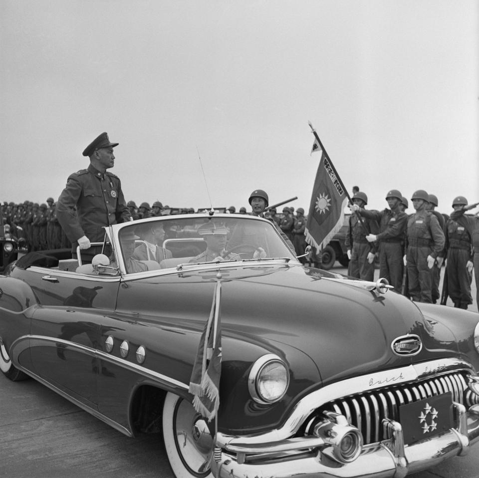 In this black-and-white photo, President Chiang Kai-shek stands in the back of a vintage Buick convertible facing dozens of troops, who stand at attention.