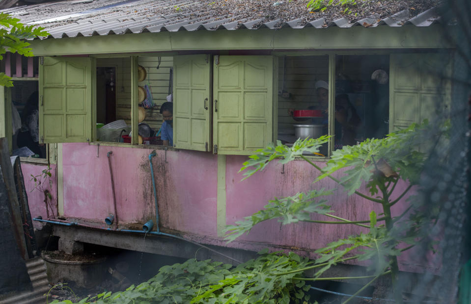 Katsane Sattapitak, right, cooks for school children at Makkasan preschool kitchen, constructed on a swamp adjoining a canal, in Bangkok, Thailand, Wednesday, June 24, 2020. The school with 100 students, aged 2-6 years serves an improvised community sandwiched between a railway line and an urban canal, including children of migrant workers from Myanmar, Laos and Cambodia. (AP Photo/Gemunu Amarasinghe)