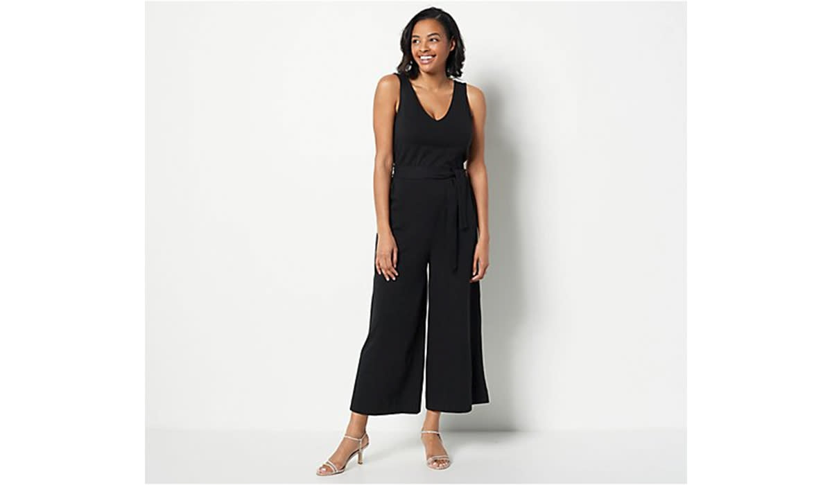 Woman wearing sleeveless black v-neck jumpsuit with heels