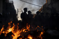 Israeli police officers stand guard next to burning garbage during clashes with ultra-Orthodox Jews in Bnei Brak, Israel, Sunday, Jan. 24, 2021. Ultra-Orthodox demonstrators clashed with Israeli police officers dispatched to close schools in Jerusalem and Ashdod that had opened in violation of coronavirus lockdown rules, on Sunday. (AP Photo/Oded Balilty)