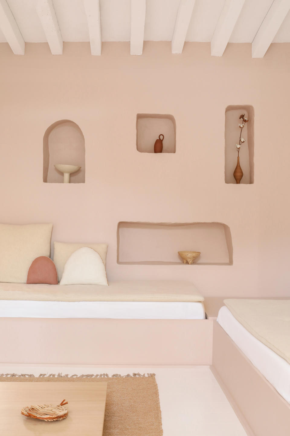 A pink living room with small niches on the walls