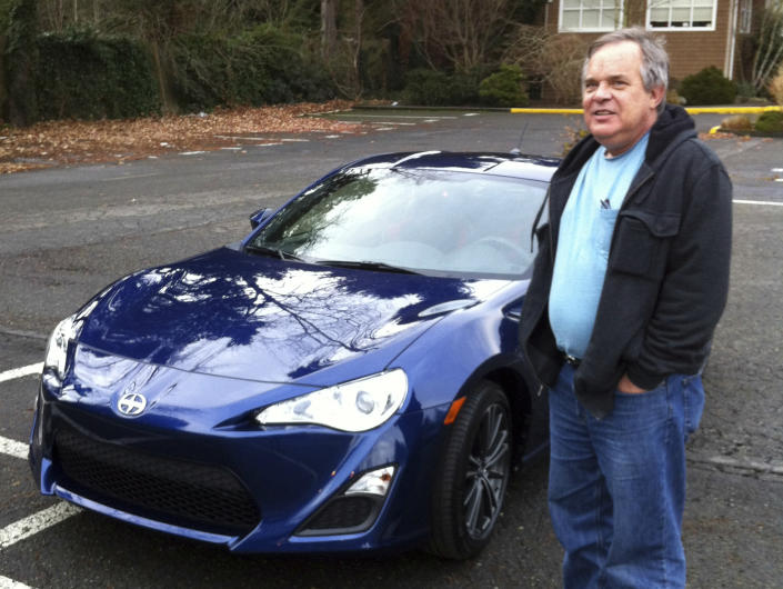 In this Dec. 14, 2013, photo, Alan Naiman poses with his new car, an unusual extravagance for him, in Seattle. (Shashi Karan via AP)