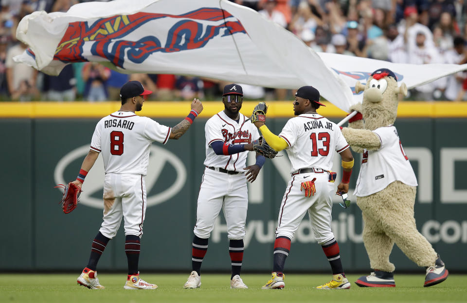 From left to right, Atlanta Braves outfielders Eddie Rosario, Guillermo Heredia, Ronald Acuna Jr. (13) and team mascot 'Blooper' celebrate a win over the Washington Nationals in a baseball game Saturday, July 9, 2022, in Atlanta. (AP Photo/Ben Margot)