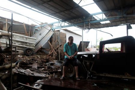 Freddy Guerrero sits amidst the remains of his auto shop, after the island was hit by Hurricane Maria in Toa Baja, Puerto Rico October 16, 2017. REUTERS/Alvin Baez