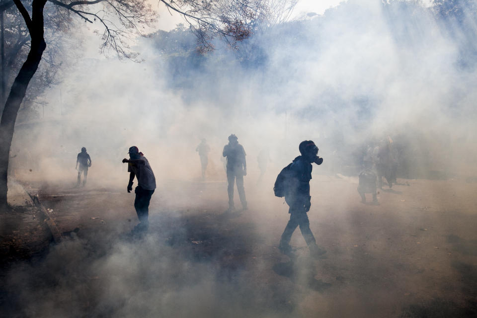 Manifestantes caminan entre el humo de bombas de gases lacrimógenas lanzadas por agentes antimontines en una protesta antigubernamental en Caracas, Venezuela, el miércoles 12 de marzo de 2014. (AP Photo/Alejandro Cegarra)