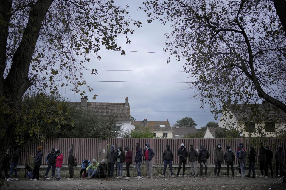 Migrants wait for food distribution at a camp in Calais, northern France, Thursday, Oct. 14, 2021. While some migrants with money can pay to go to Britain on flimsy, overcrowded boats in often dangerous waters, the ones who can’t have to jump on one of the tens of thousands commercial trucks that pass each week between France and Britain. (AP Photo/Christophe Ena)