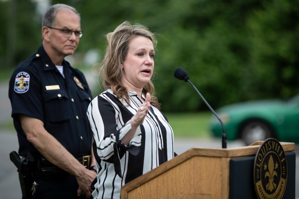 Police Chief Steve Conrad, left, looks on as Rebecca Grignon speaks during the renaming of the corner of Stony Brook Drive and Six Mile Lane in Jeffersontown to Peter Grignon Way, in honor of her late husband and fallen officer shot during a hit and run stop in 2005. May 9, 2019