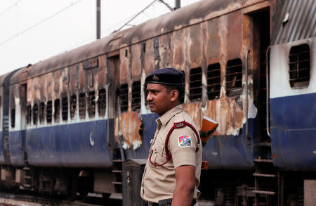 A security personnel member stands guard outside a burnt carriage of a train near a railway station in New Delhi, India, August 26, 2017. REUTERS/Adnan Abidi