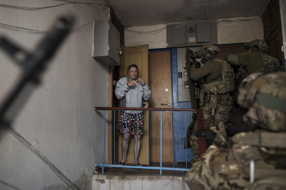 FILE - A woman looks as Security Service of Ukraine (SBU) servicemen enter a building during an operation to arrest suspected Russian collaborators in Kharkiv, Ukraine, Thursday, April 14, 2022. Ukrainian authorities are cracking down on anyone suspected of aiding Russian troops under laws enacted by Ukraine’s parliament and signed by President Volodymyr Zelenskyy after the Feb. 24 invasion. Offenders face up to 15 years in prison for acts of collaborating with the invaders or showing public support for them. (AP Photo/Felipe Dana, File)