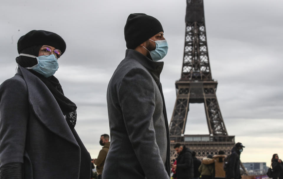 People wearing face makes to protect against the COVIS-19 walk at Trocadero plaza near Eiffel Tower in Paris, Saturday, Dec. 26, 2020. French health authorities have confirmed the country's first case of the virus variant that prompted strict new lockdown measures in Britain and global travel restrictions.(AP Photo/Michel Euler)