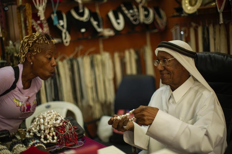 A former pearl diver Saad Ismail talks to a client in his pearl shop in Souq Waqif market in Doha, Qatar, Saturday, Nov. 19, 2022. (AP Photo/Francisco Seco)
