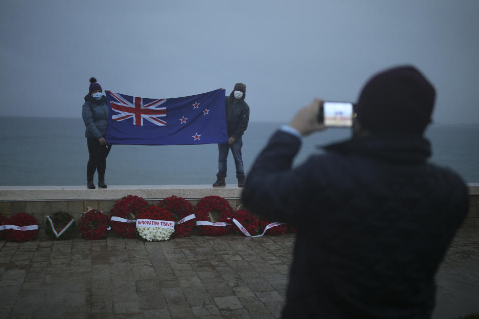 People hold a flag of New Zealand as they are photographed following the Dawn Service ceremony at the Anzac Cove beach in Gallipoli peninsula, the site of World War I landing of the ANZACs (Australian and New Zealand Army Corps) on April 25, 1915, in Canakkale, Turkey, early Sunday, April 25, 2021. The dawn service ceremony and all other commemorative ceremonies for the 106th anniversary honouring thousands of Australians and New Zealanders who fought in the Gallipoli campaign of World War I on the ill-fated British-led invasion, were small and held without public this year due to the coronavirus pandemic.(AP Photo/Emrah Gurel)