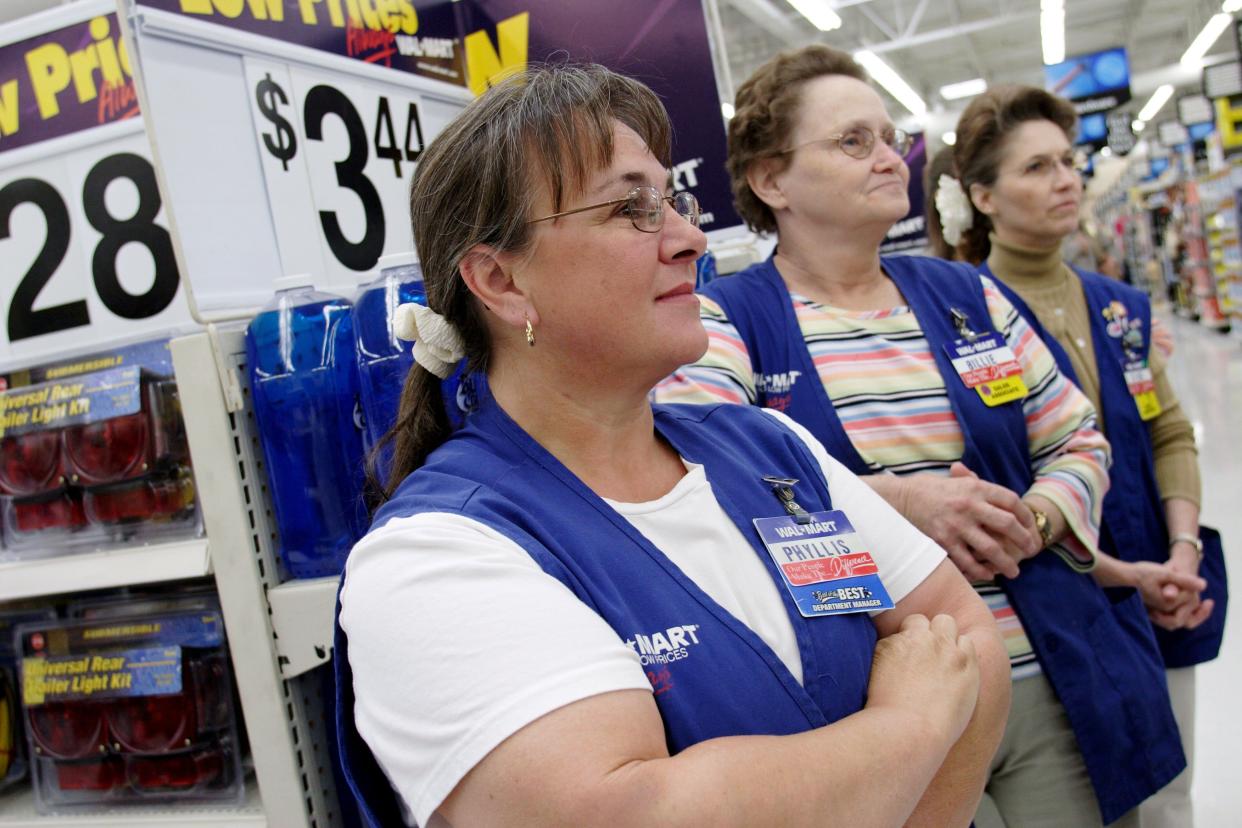 emale Wal-Mart employees look on as a manager rewards an employee with a plaque