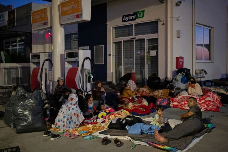 Refugees and migrants find shelter outside a gas station, following a fire at the Moria camp on the island of Lesbos