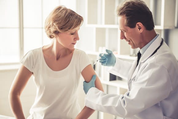 Male doctor giving a female patient an injection