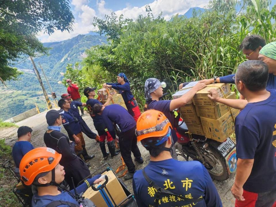 因道路通行受阻，搜救團隊只能透過徒手攀爬，靠近受困地點，以人力接龍搬進物資。（翻攝自新北消防發爾麵）