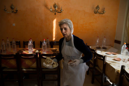 Retired teacher and volunteer Eva Agkisalaki clears tables at a soup kitchen run by the Orthodox church in Athens, Greece, February 15, 2017. REUTERS/Alkis Konstantinidis