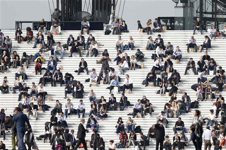 Businessmen enjoy the good weather at lunch time on the steps of the Arche de la Defense, in the financial and business district west of Paris, as warm and sunny weather continues in France, March 13, 2014. REUTERS/Charles Platiau