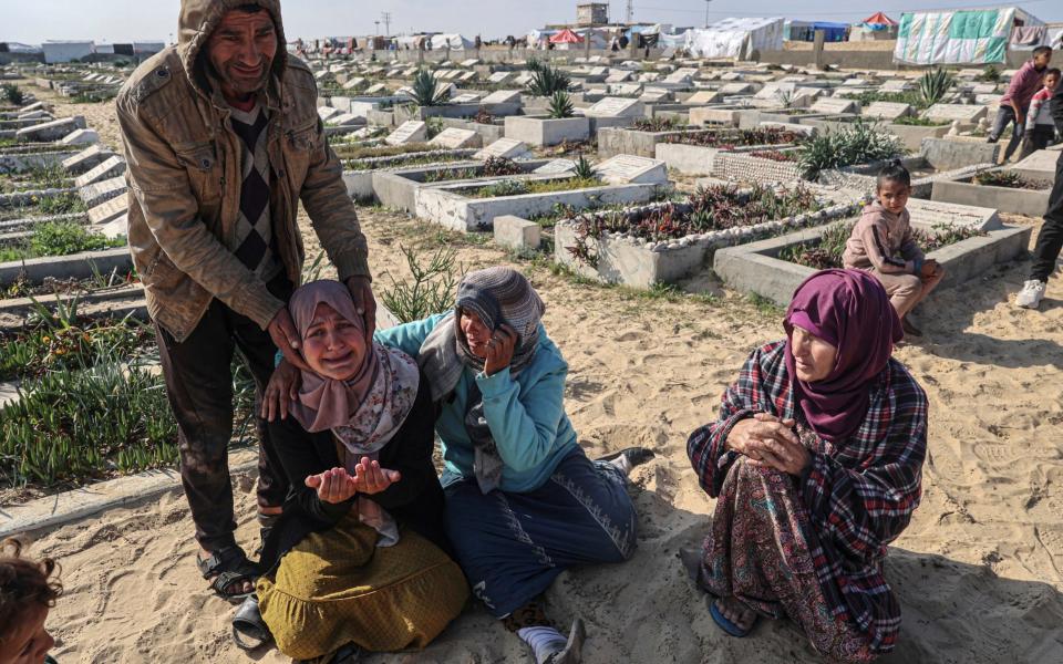 Relatives mourn during the funeral of loved ones killed during overnight Israeli strikes at a cemetery in Rafah