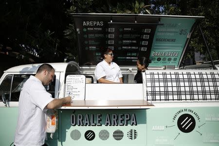 Venezuelan chef Jorge Udelman (L), 34, prepares to serve Venezuelan food on his food truck called "Orale Arepa", at a parking lot in Mexico City March 30, 2014.