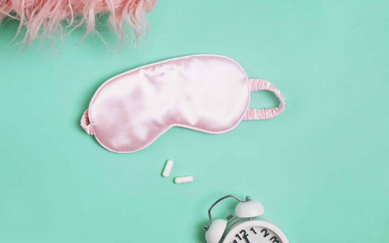 Pink sleeping mask, alarm clock and two pills  - iStockphoto 