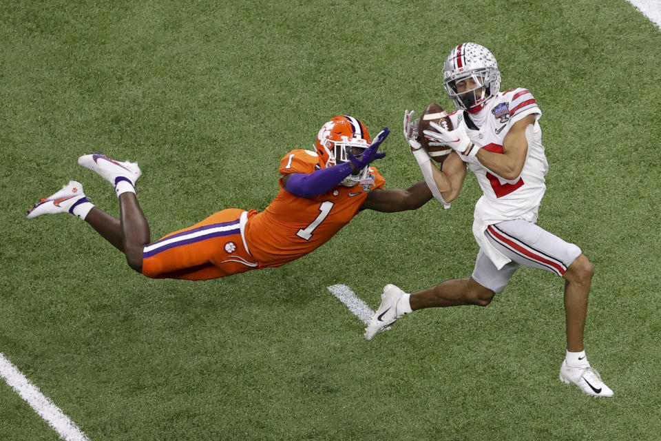 FILE - In this Friday, Jan. 1, 2021, file photo, Ohio State wide receiver Chris Olave catches a touchdown pass in front of Clemson cornerback Derion Kendrick during the second half of the Sugar Bowl NCAA college football game in New Orleans. In an announcement posted on social media, Monday, Jan. 18, 2021, Olave said he is returning to Ohio State for his senior year. (AP Photo/Butch Dill, File)