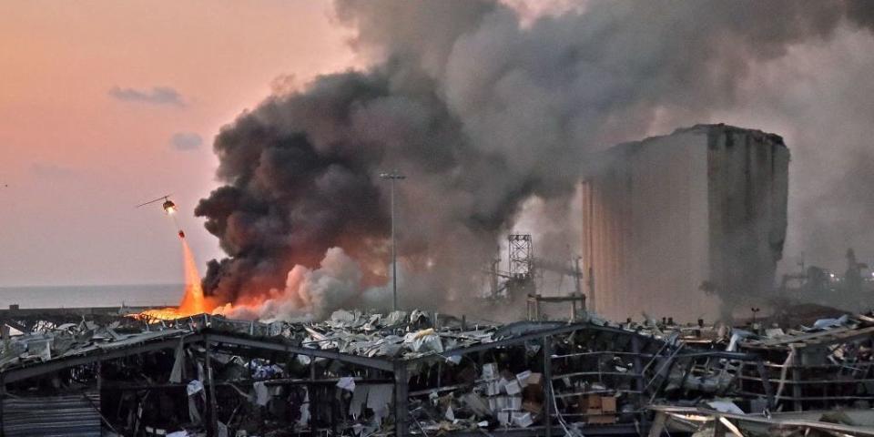 A helicopter puts out a fire at the scene of an explosion at the port of Lebanon's capital Beirut on August 4, 2020.