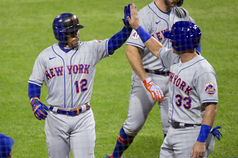 New York Mets Francisco Lindor (12) high fives James McCann (33) after McCann scored on Lindor's sacrifice fly during the seventh inning of a baseball game against the Philadelphia Phillies, Tuesday, April 6, 2021, in Philadelphia. (AP Photo/Laurence Kesterson)