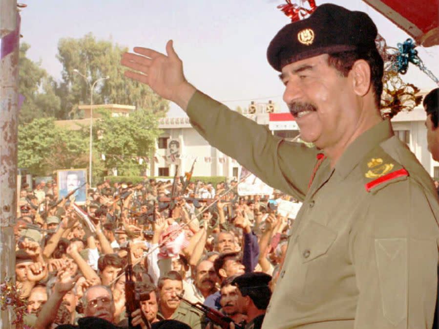FILE – Iraqi President Saddam Hussein waves to his supporters in his first public appearance in Baghdad on Oct. 18 since he was reelected as President for seven years in a referendum with 99.96 percent of the votes. (INA/AFP via Getty Images)