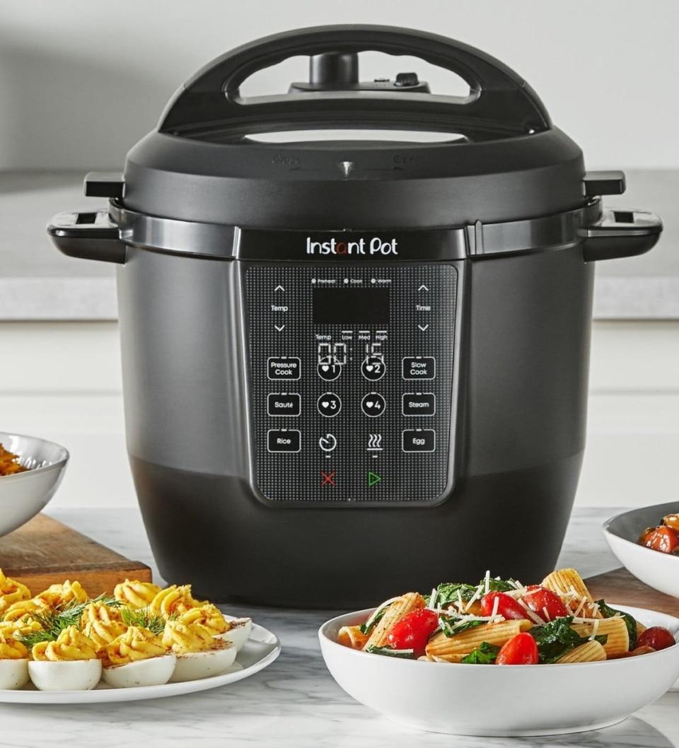 Black Instant Pot on a kitchen counter with assorted dishes around it