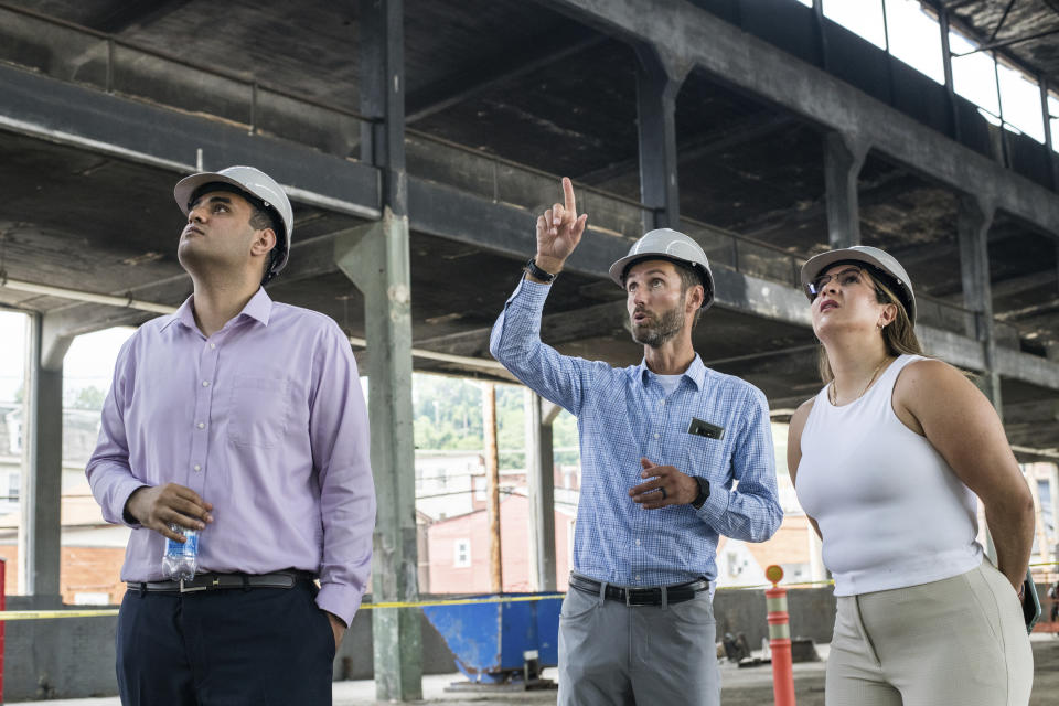 From left, AM Group co-workers Amaan Chaudry, of New York, Matthew Cypher, of Arlington, Va., and Mariana Rios, of New York, look at the space at 51 Bridge Street during a celebration marking the start of renovations to turn the former steel pipe manufacturing building to a 88,600 square-foot tech flex facility, Thursday, July 15, 2021, in Etna, Pa. The facility is geared to become a hub for a small number of companies focused on tech, robotics, and AI. (Stephanie Strasburg/Pittsburgh Post-Gazette via AP)