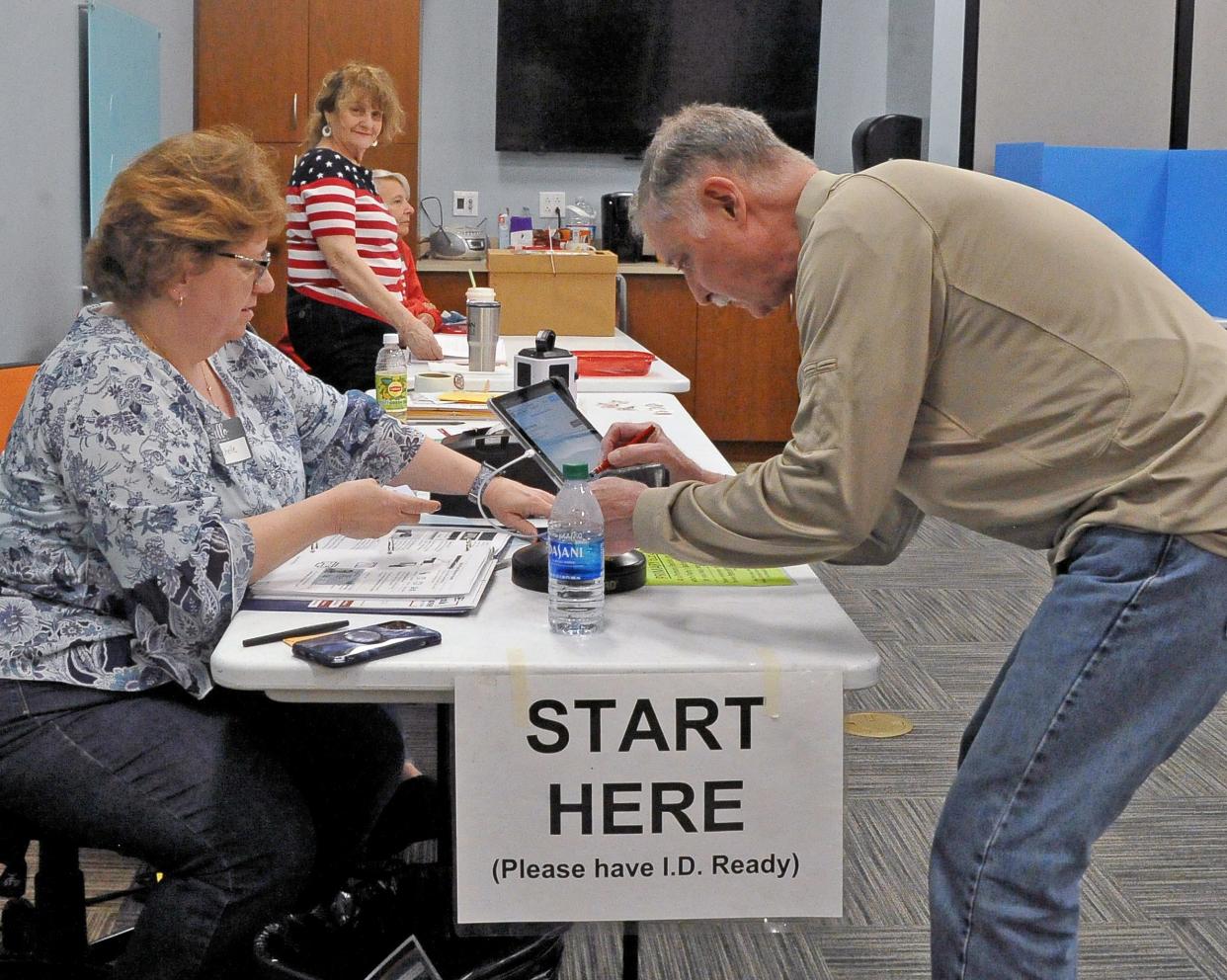 Dalton Public Library poll worker Michelle Gibson helps Dale Flickinger as he signs in to vote Tuesday morning.