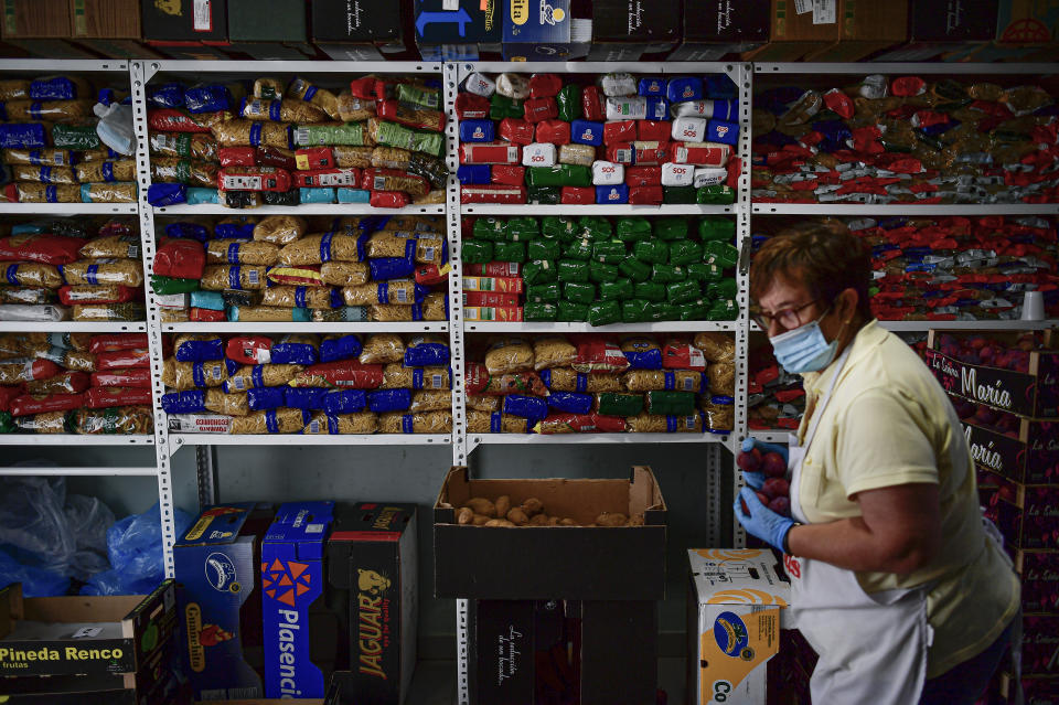 Conchi Uriz, 69 years old and volunteer of the charity foundation Caritas, wears face mask to prevent the coronavirus as she prepares a pack of foods, in Estella, around 38 kms (23, 61 miles) from Pamplona, northern Spain, Wednesday, July 1, 2020. Spain is beginning to suffer an economic crisis due to the coronavirus pandemic. (AP Photo/Alvaro Barrientos)