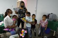 Varios niños sostienen juguetes que les regalaron mientras esperan ser vacunados durante una campaña del gobierno de inoculaciones contra el polio, la rubeola y la influenza en Caracas el 18 de junio del 2022. (AP Photo/Ariana Cubillos)