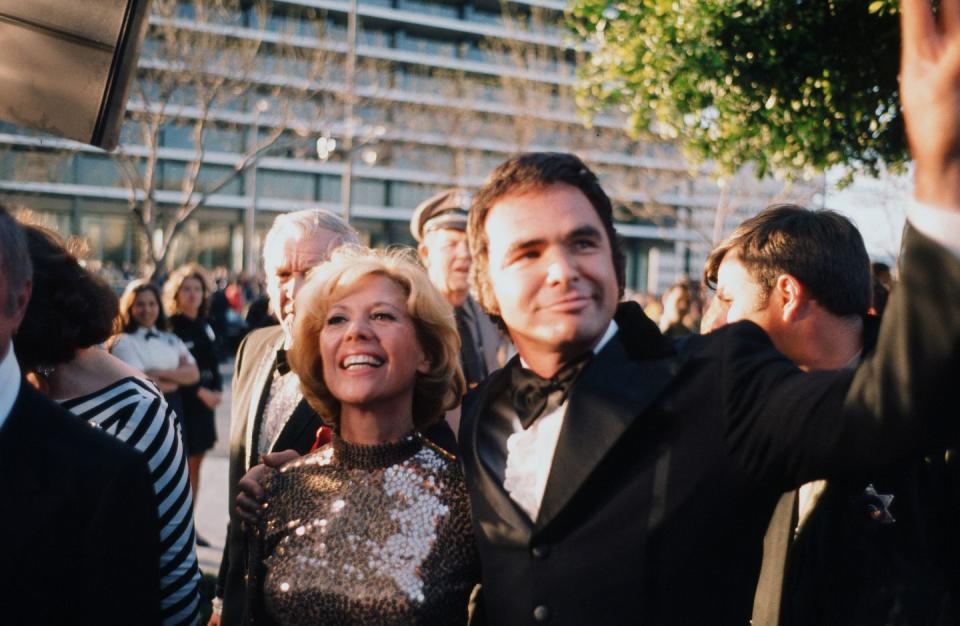 <p>Reynolds gives a wave to fans as he and Dinah Shore arrive at the 46th Annual Academy Awards in 1974. The actor sported impressive sideburns f0r the event.</p>