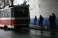 In this Sunday, Feb. 3, 2019, photo, people stand under a bridge as tram drives by in Pyongyang, North Korea. Pyongyang is upgrading its overcrowded mass transit system with brand new subway cars, trams and buses in a campaign meant to show leader Kim Jong Un is raising the country's standard of living. (AP Photo/Dita Alangkara)