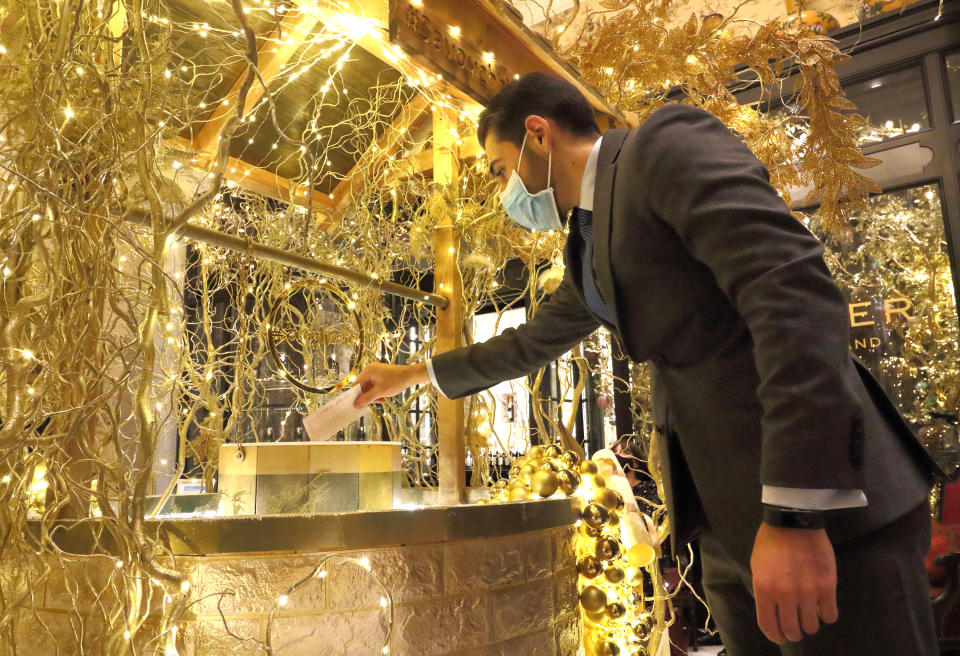 LONDON, UNITED KINGDOM - 2020/12/03: A member of staff wearing a mask posts a wish into the golden wishing well.
The Savoy Hotel has reopened and launched a new Christmas charity initiative - Festive Wishes. Launched as the hotel showcases its famous Christmas decorations, The Savoy will grant wishes rewarding kindness and in doing so support two key charities, namely Hospitality Action and The Connection at St Martin in the Fields. (Photo by Keith Mayhew/SOPA Images/LightRocket via Getty Images)