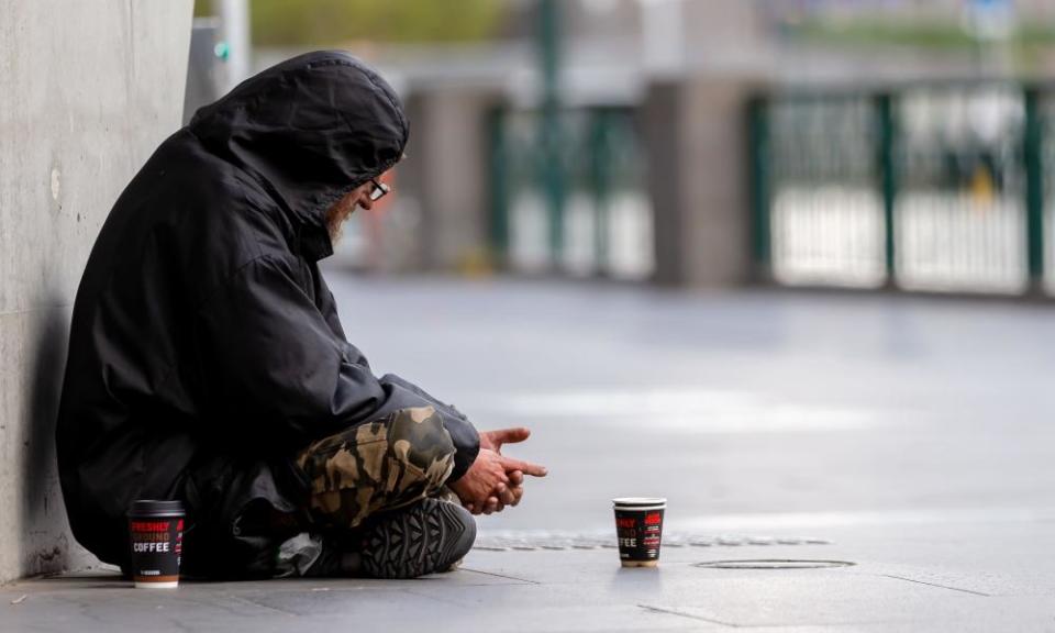 A homeless man sits on the banks of the Yarra River