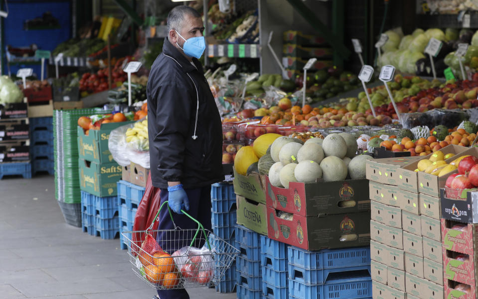 A man wears a face mask to protect against the coronavirus as he shops at a fruit and vegetable shop in London, Wednesday, April 29, 2020. The Scottish Government is recommending the use of masks in shops and public transport, and Mayor of London Sadiq Khan has called for people to wear facemasks, while the British government has refused to recommend the face covering.(AP Photo/Kirsty Wigglesworth)